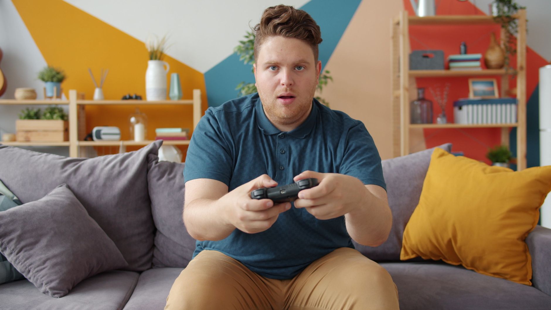 A young man intensely playing video games in a modern living room setting. — Benefits of Choosing a Highly Ranked Safe Playgr