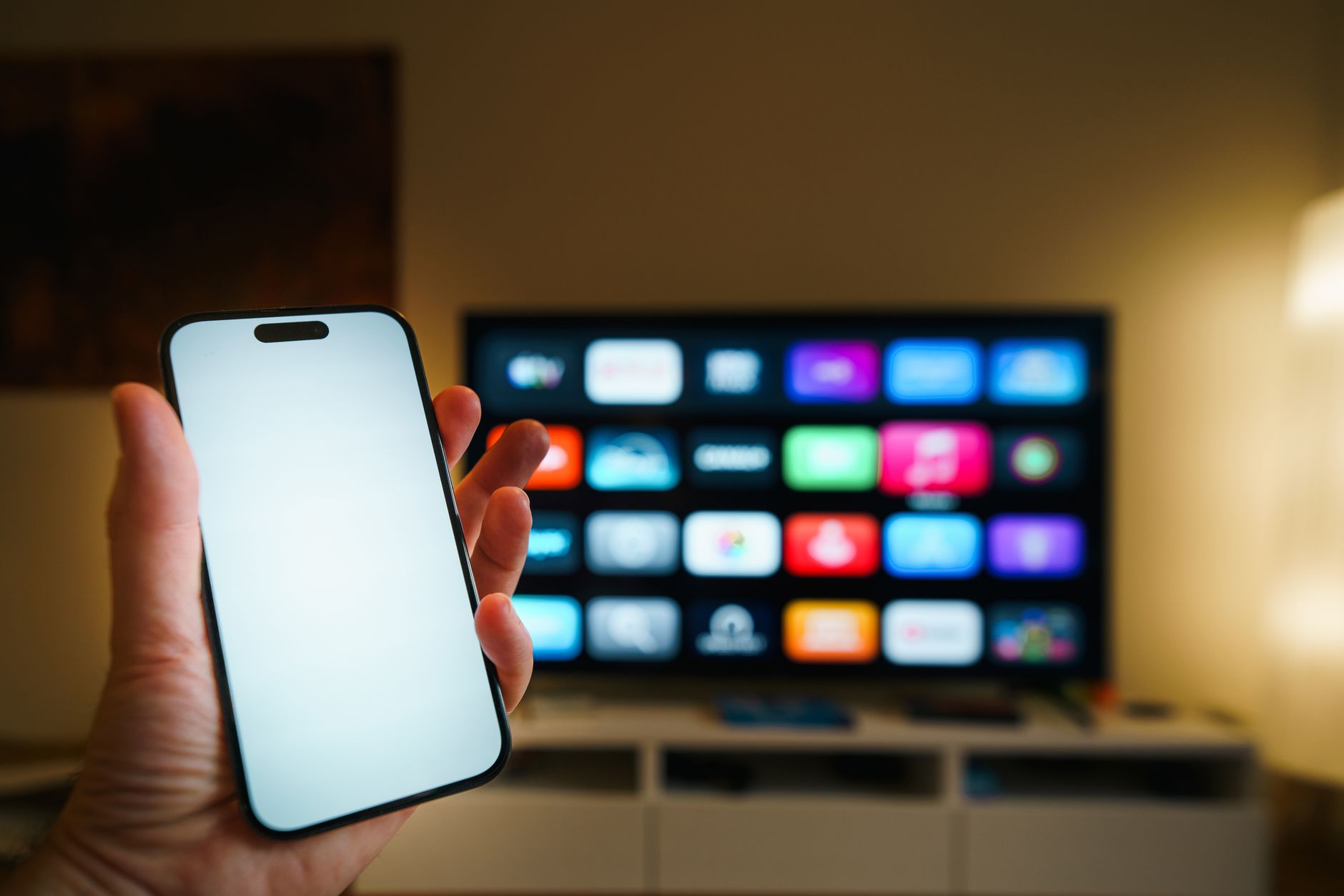 A smartphone in focus with a smart TV displaying apps in a cozy living room. — Jeonguk TV Brings You Premium Sports Broadcast