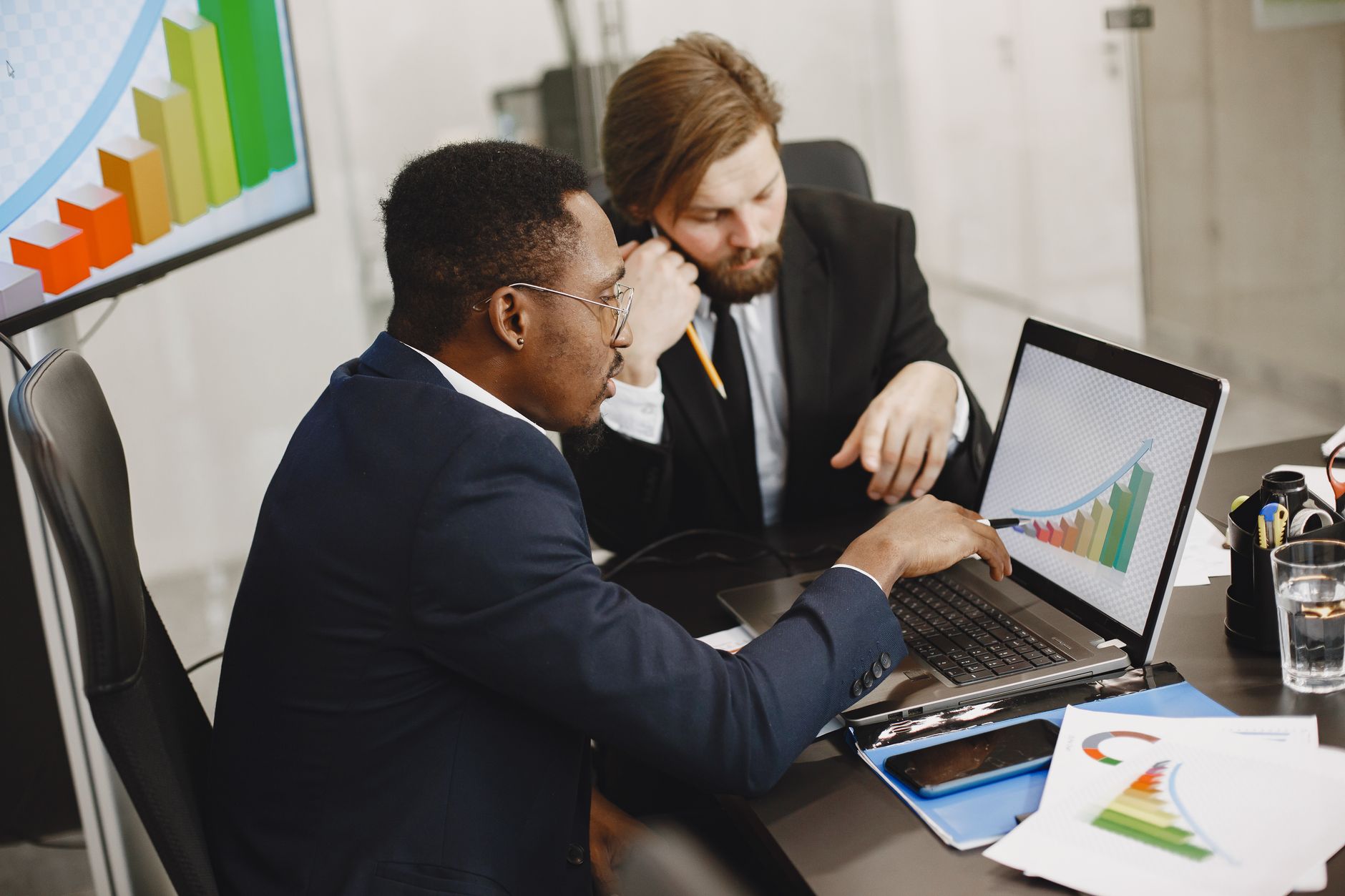 Two business professionals working on growth charts using laptop in an office setting. — Nextcloud Hosting: Everything You Ne