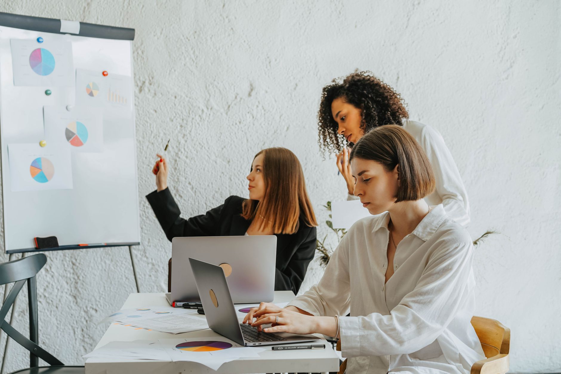 Women working together on a business project with laptops and charts. Collaborative and diverse environment. — Organic SEO Vs