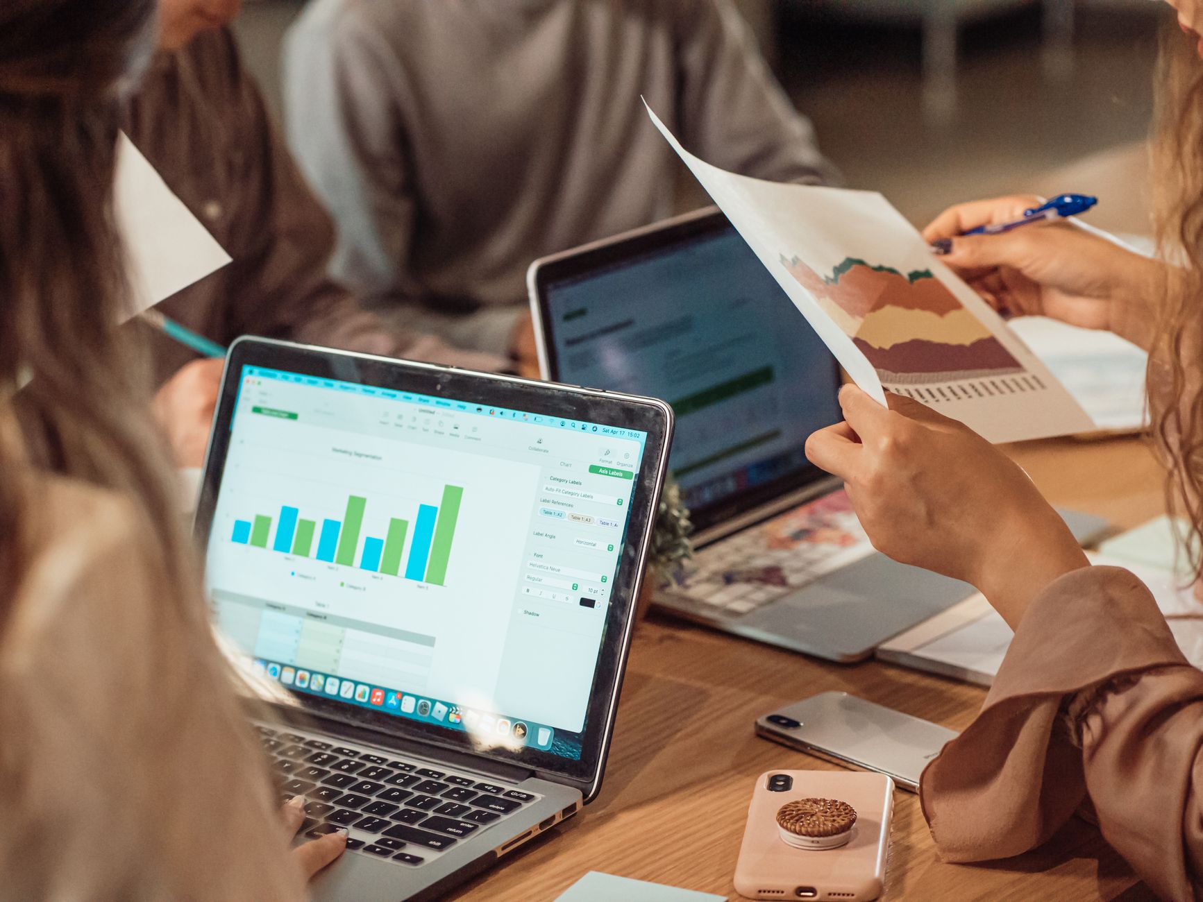 A group engaged in a business meeting analyzing charts on laptops and papers. — Some Of The Advantages Of Digital Marketing