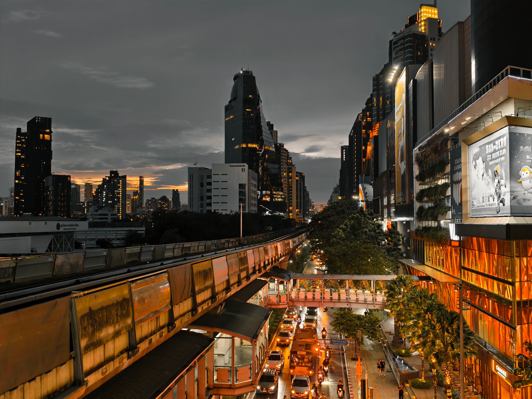 Cityscape at twilight showing busy traffic, skyscrapers, and an elevated train line in an urban setting. — Why You Need to Bu
